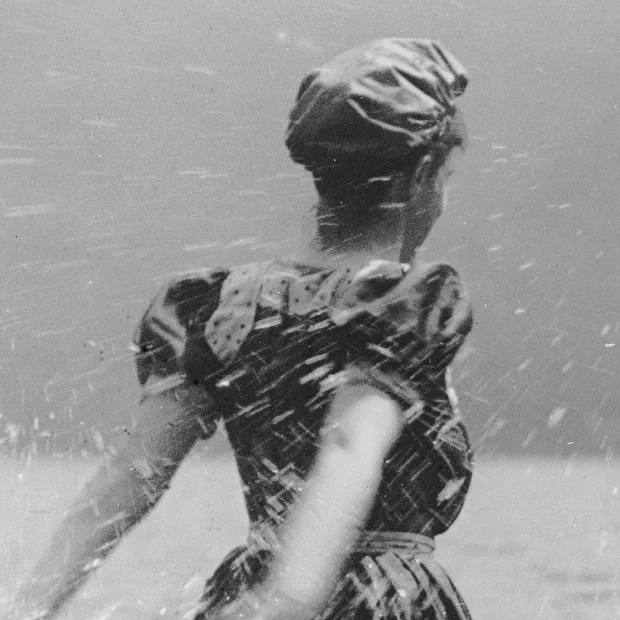 Mulher na praia, a salpicar água.